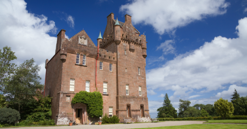 Historic stone castle surrounded by greenery under a bright blue sky, perfect for exploring on a small group tour in the UK.