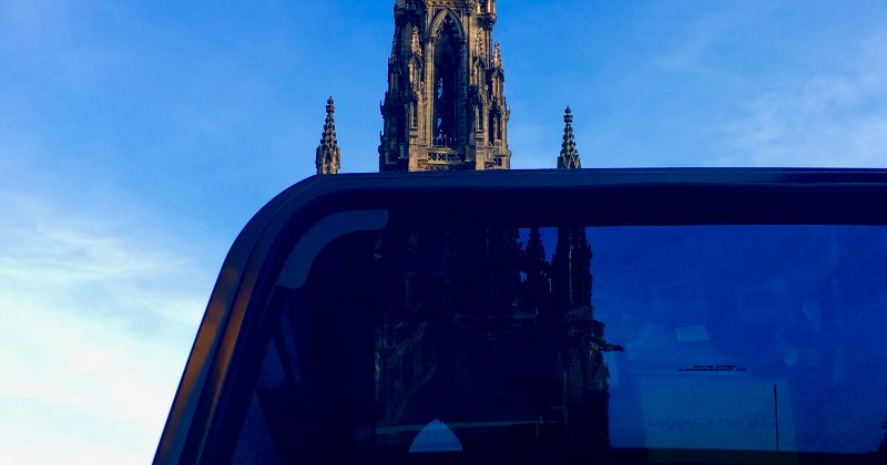 A scenic view featuring a tour vehicle with a historic tower in the background under a clear blue sky.