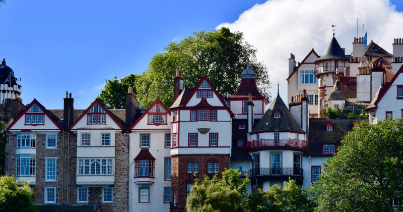 Colorful buildings with distinct architecture, surrounded by greenery under a clear blue sky.