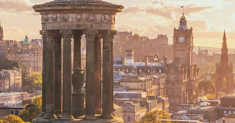 A columned building overlooking an old city at sunset