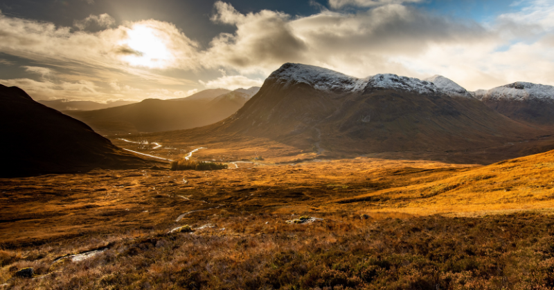 the sun setting over a valley and mountains