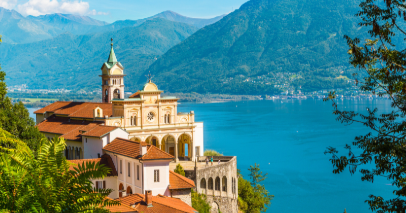 bright blue lakes and green mountains in the background with a light stone building in front