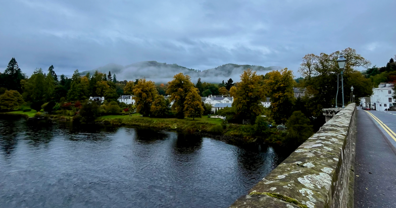 A bridge overlooking a river with misty mountains in the background