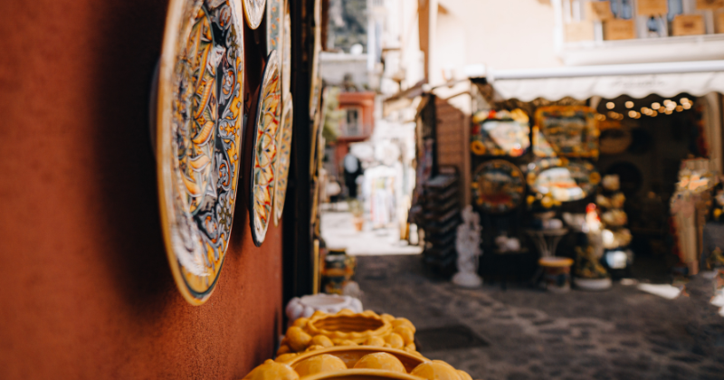 Colorful handcrafted plates adorn a narrow street, leading to quaint shops and vibrant displays of local art and culture.
