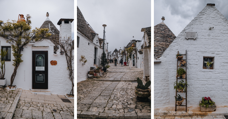 Charming white stone houses with unique roofs lining a cobblestone street, featuring greenery and quaint decorations.