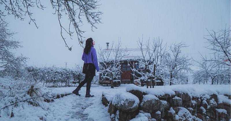 girl in snow in front of cabin
