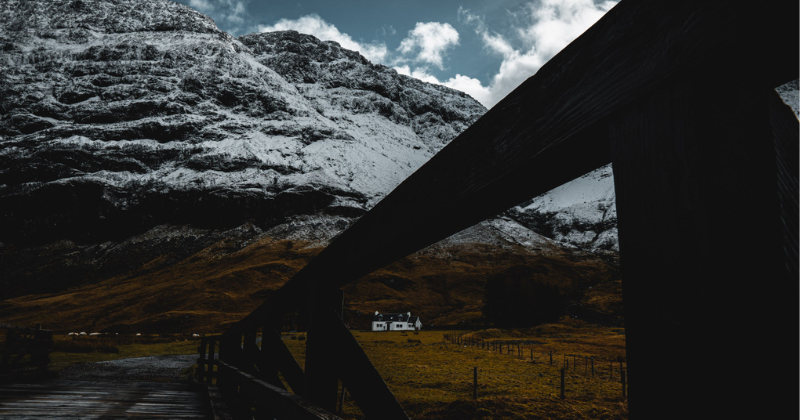 A white house in a valley underneath a snow capped mountain