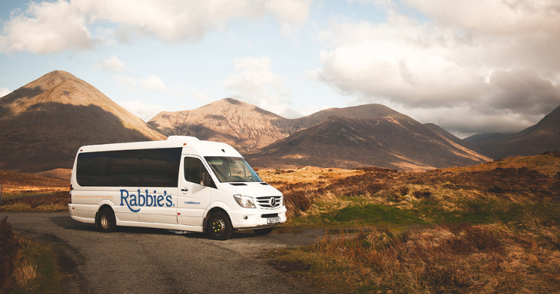 a rabbies bus in a valley in front of mountains