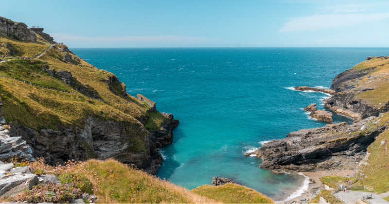 Scenic coastal view featuring cliffs, turquoise waters, and a serene beach, ideal for small group tours in the UK.