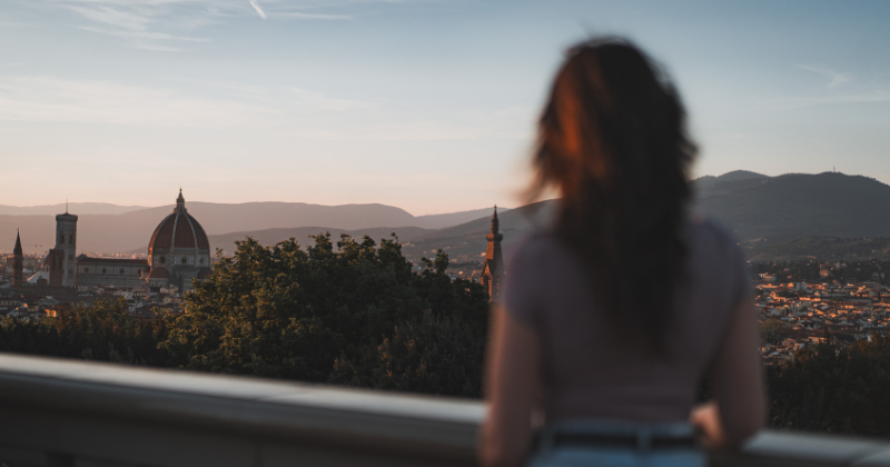 back of a persons head and body facing the rooftops of florence