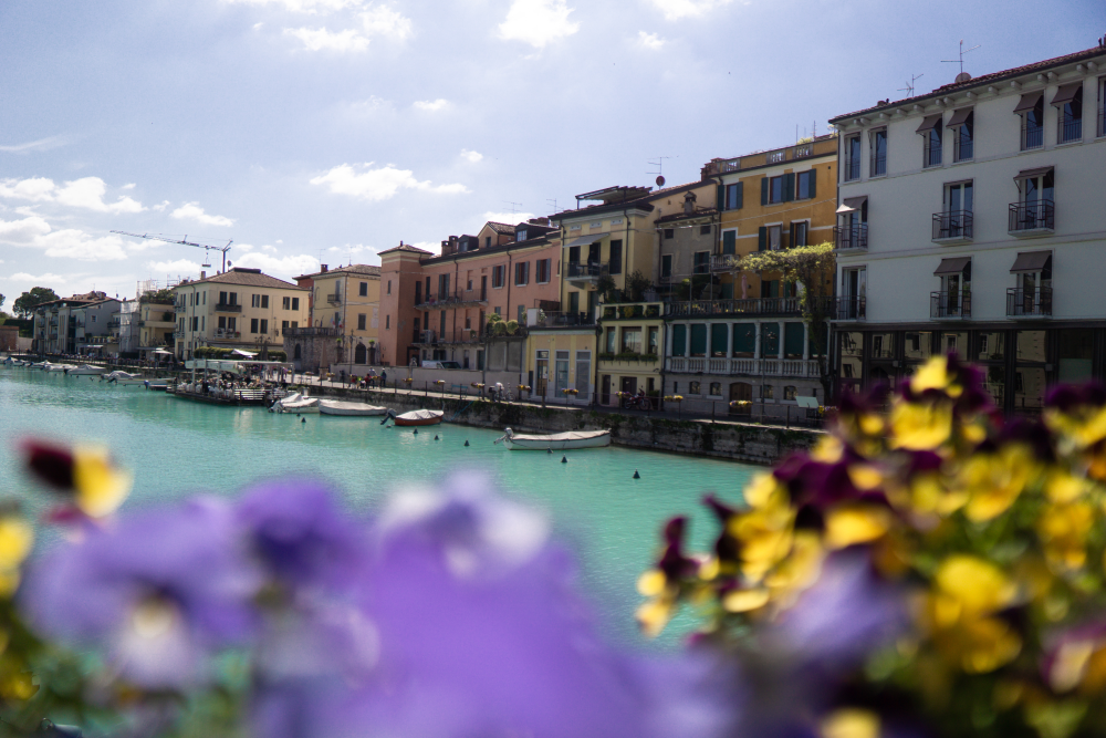 lake garda view between flower beds looking at the colourful buildings and river