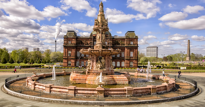 large water fountain with a large house in the background on a cloudy summer day