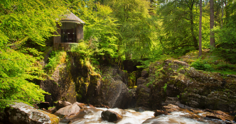 a stone building surrounded by green trees