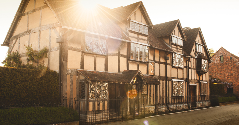 shakespeare house front with black beams and the golden sun shining behind