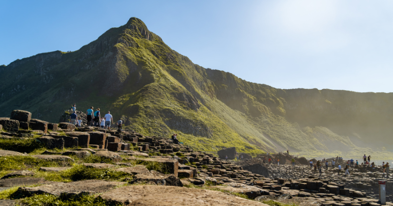 rocky stone of the Giants Causeway with a green mountain in the background