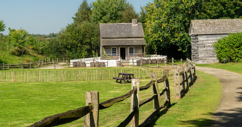 small house surrounded by green fields and a surrounding fence