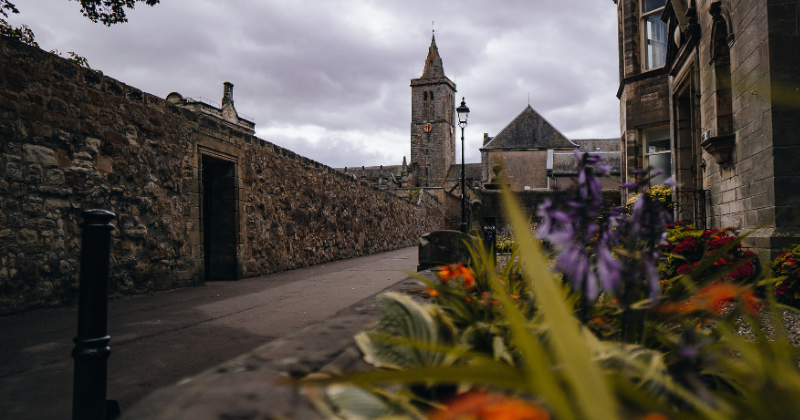 a corner of St Andrews with flowers in front and a clock tower in the background