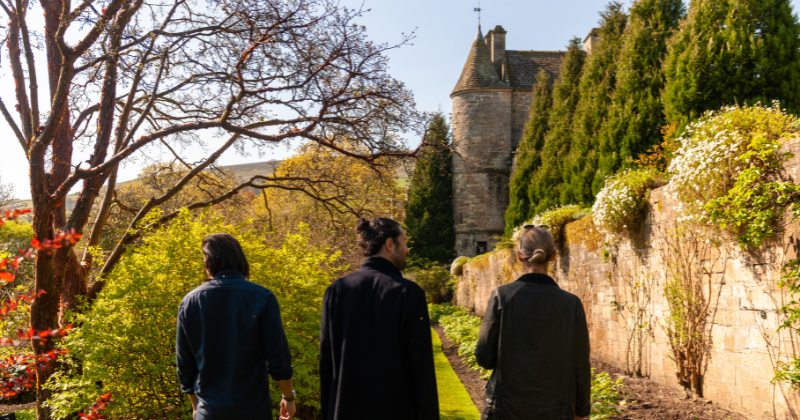 three people with their backs to the camera walking along a nature walk