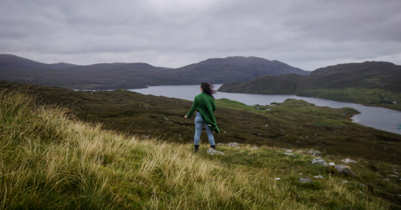 woman standing looking out to the rocky landscape with a green jacket on