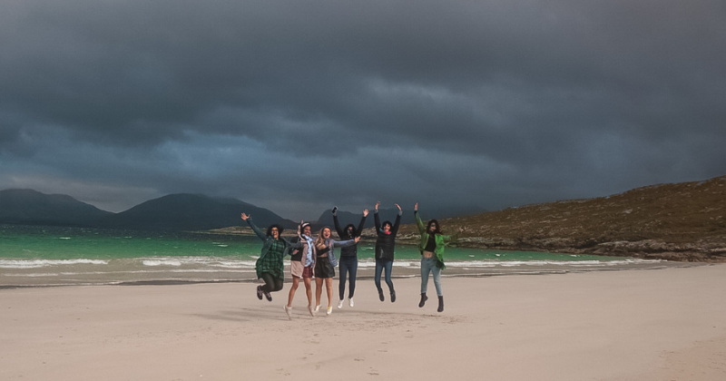 six people jumping up in the air on a beach