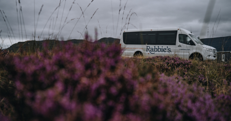 Rabbie's bus with purple heather in the foreground