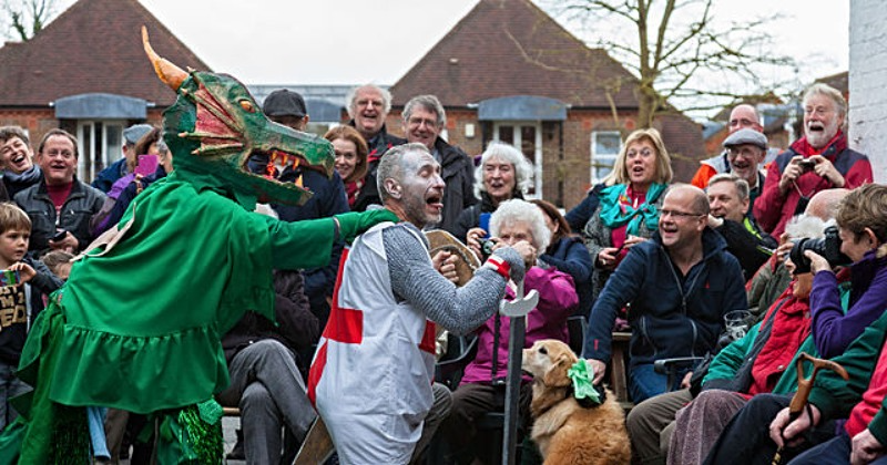 group of people surrounding a reenactment of st george and a dragon