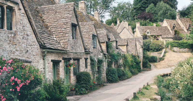 old stoned houses with green bushes out the front and a path to walk along