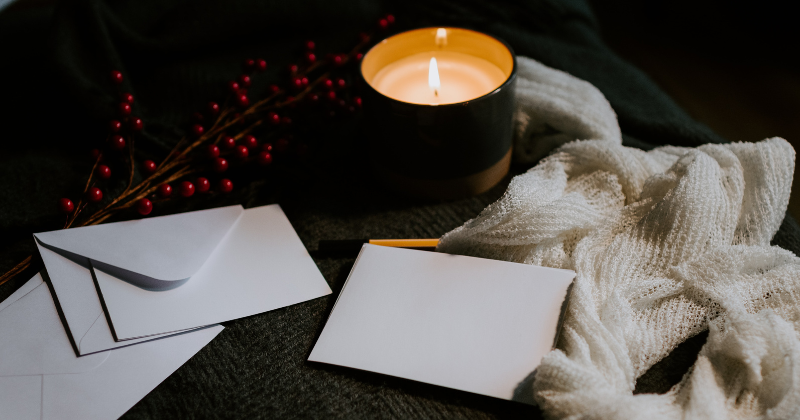 candle lit and surrounded by paper and evelopes