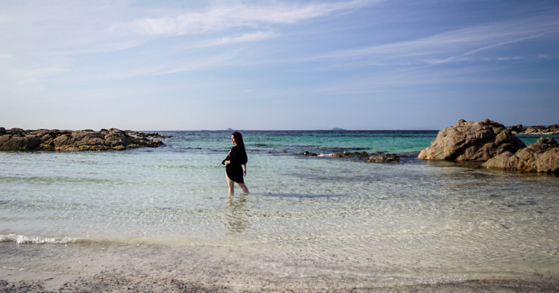 woman stood in the sea with rocks in the background