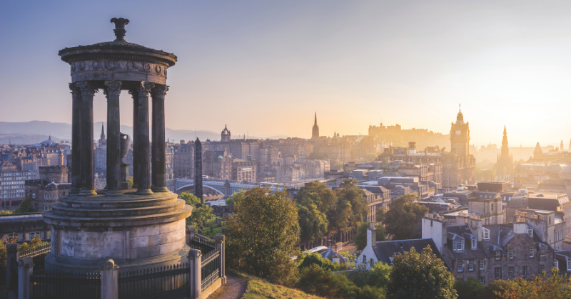 a stone monument overlooking a city at sunset