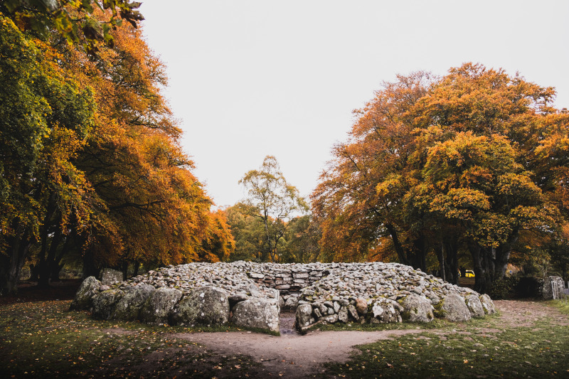 entrance of clava cairns stones during autumn with the trees showing orange leaves