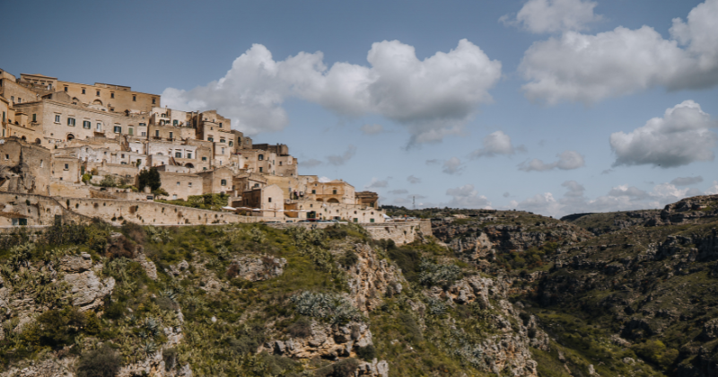 hill side with light stone coloured buildings and rocky hills to the right hand side
