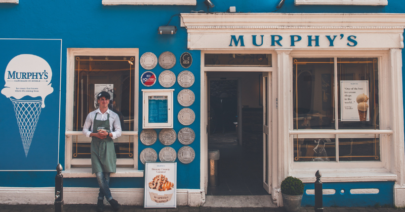 ice cream shop front with worker holding a pot of ice cream