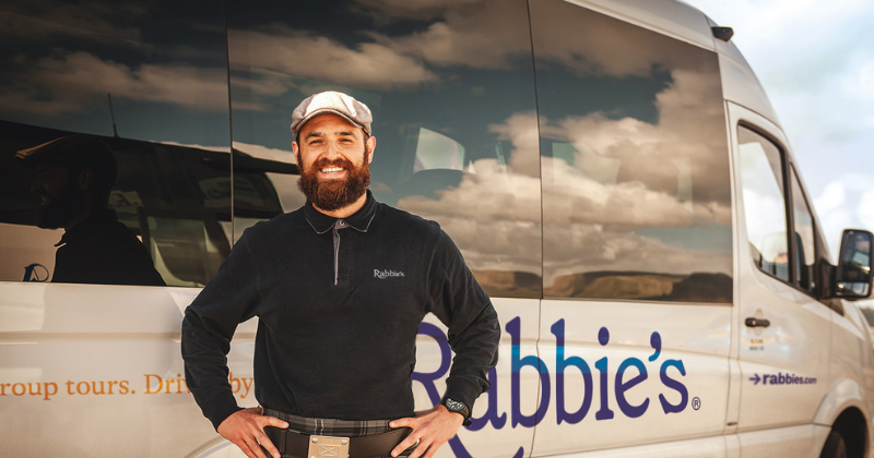 Rabbie's driver-guide stood smiling in front of a Rabbie's mini bus