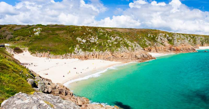 white beach in the rocky bay with blue water close by