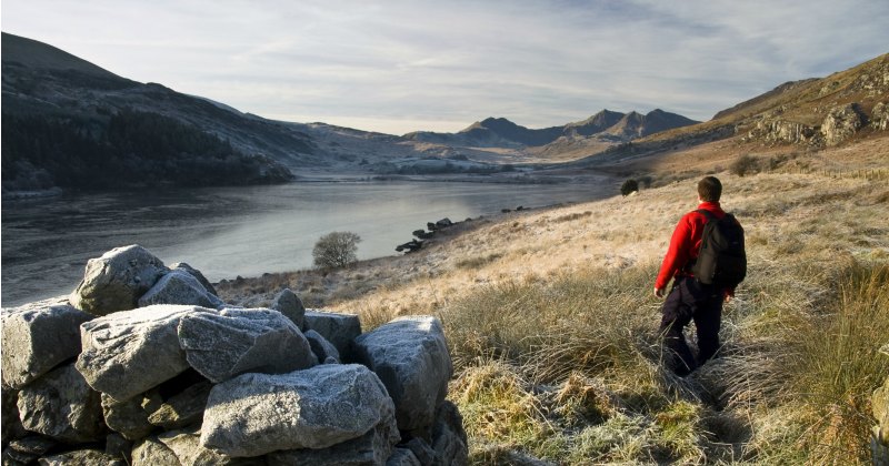 a man in a red jumper looking out over the mountain landscape around him