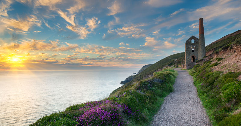 coastal path with small stone building at the end and the sea to the left