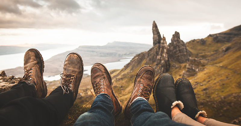 three peoples shoes with mountain landscape in the background