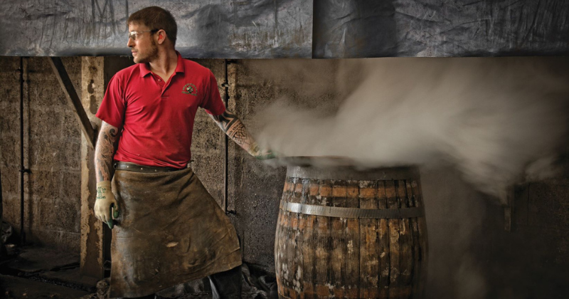 A skilled craftsman working with steam and a wooden barrel in a workshop, showcasing traditional craftsmanship and techniques.