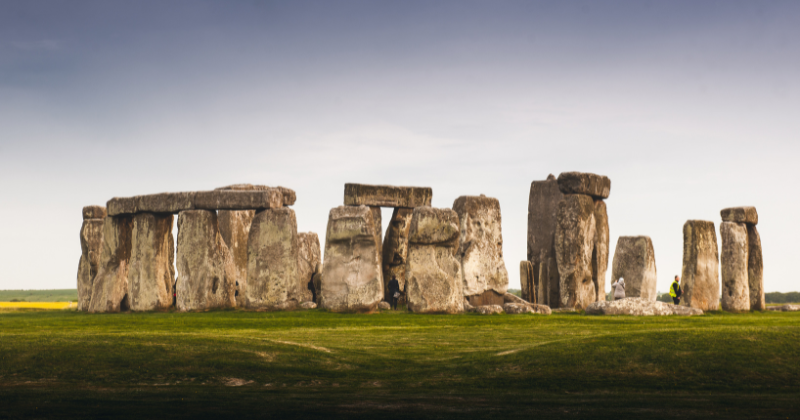Stonehenge's iconic stone circle set against a serene sky, surrounded by lush green grass, inviting exploration and wonder.