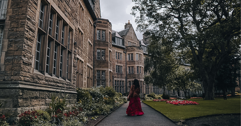 A girl walking a path by a stone building