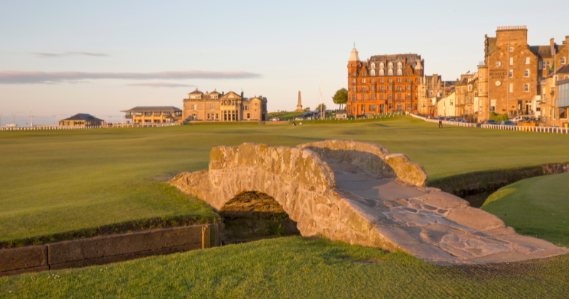 a stone bridge on a golf course at sunset