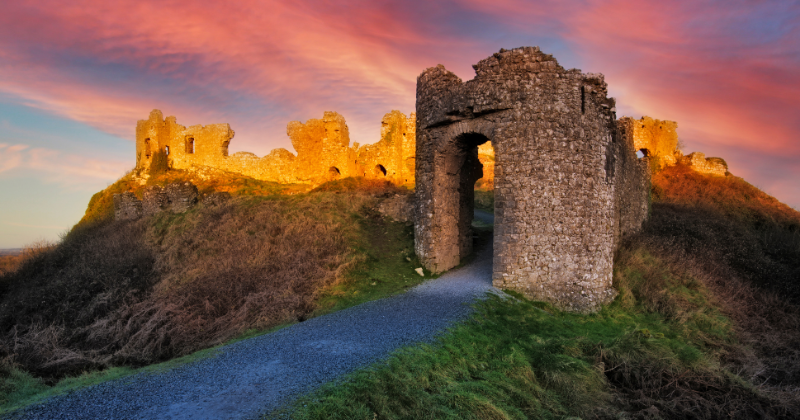 ruins of a castle with a pink hue sky above