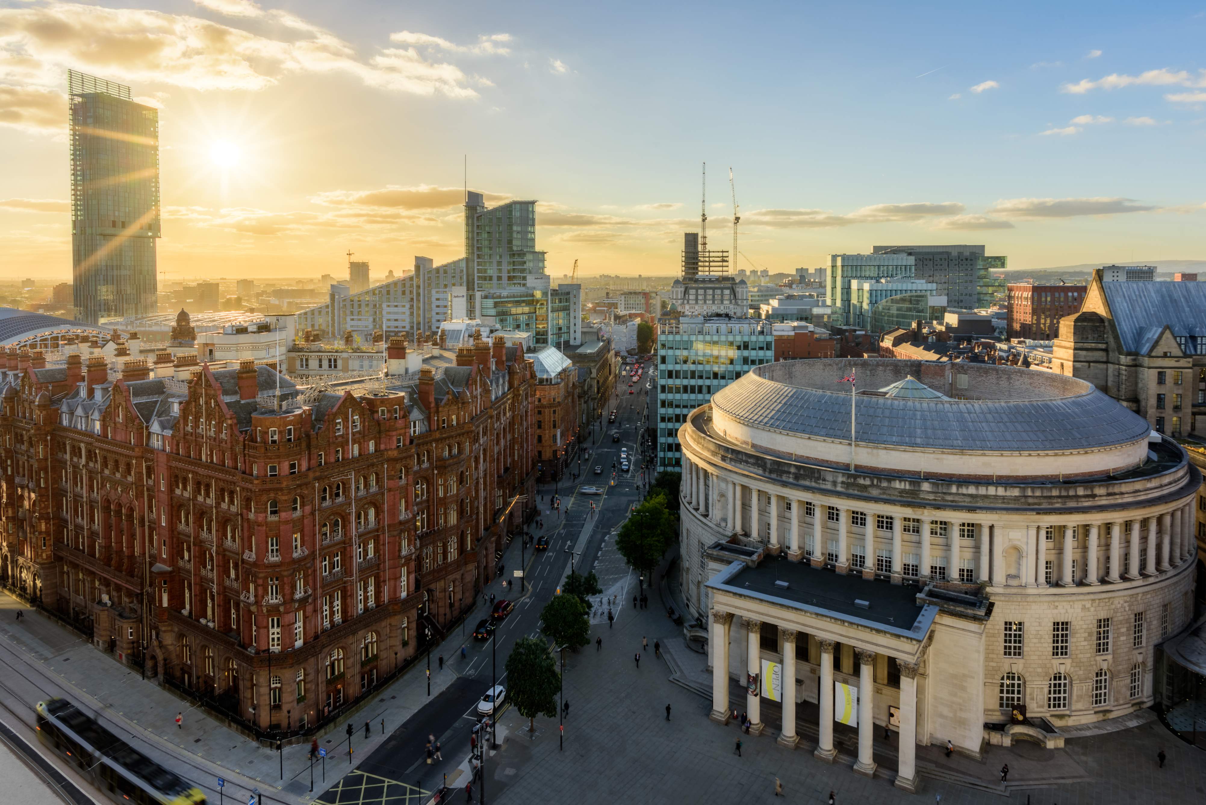 Sunset over a cityscape featuring a mix of historic and modern architecture, with bustling streets below.