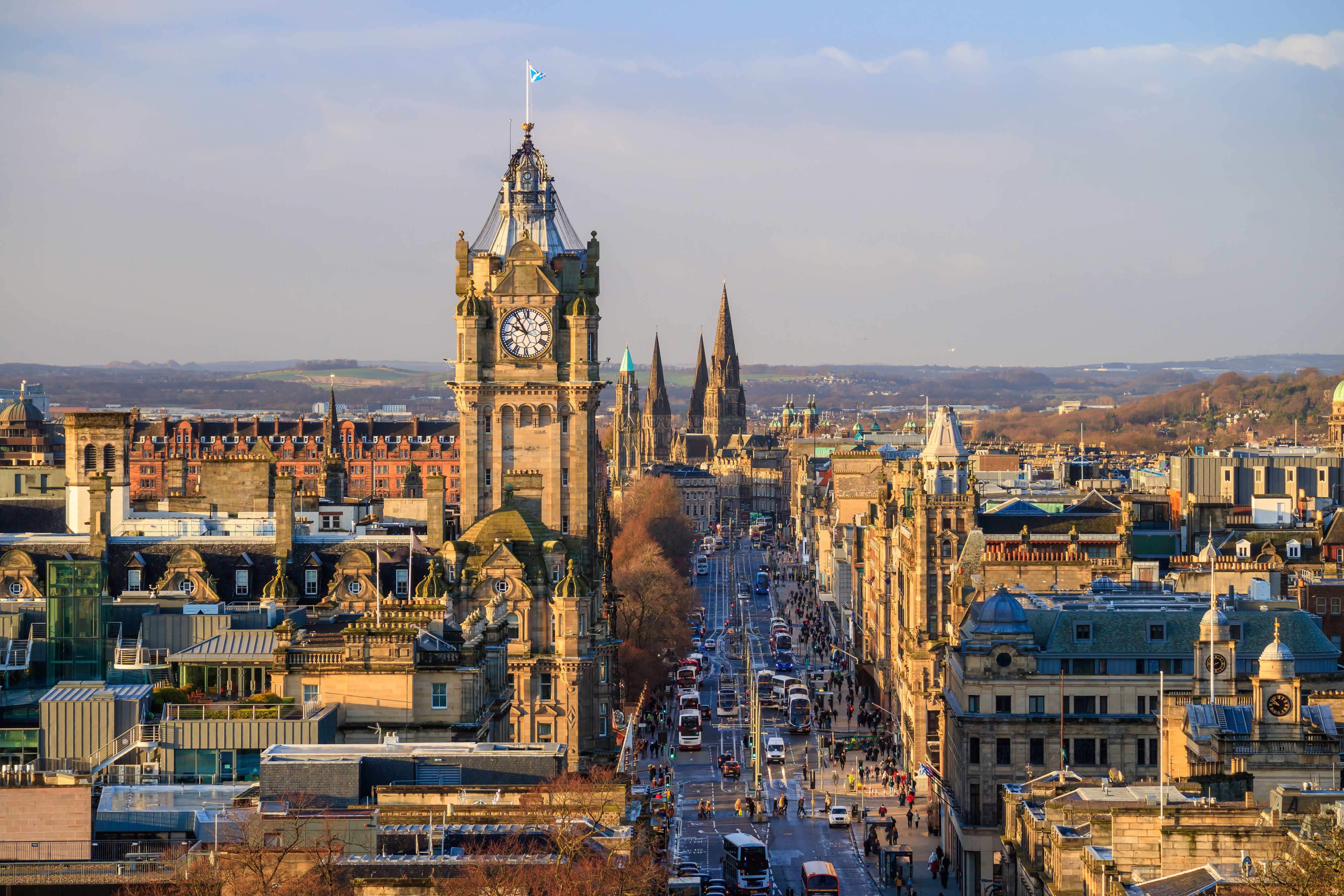Panoramic view of Edinburgh showcasing the iconic clock tower and historic buildings along a bustling street.