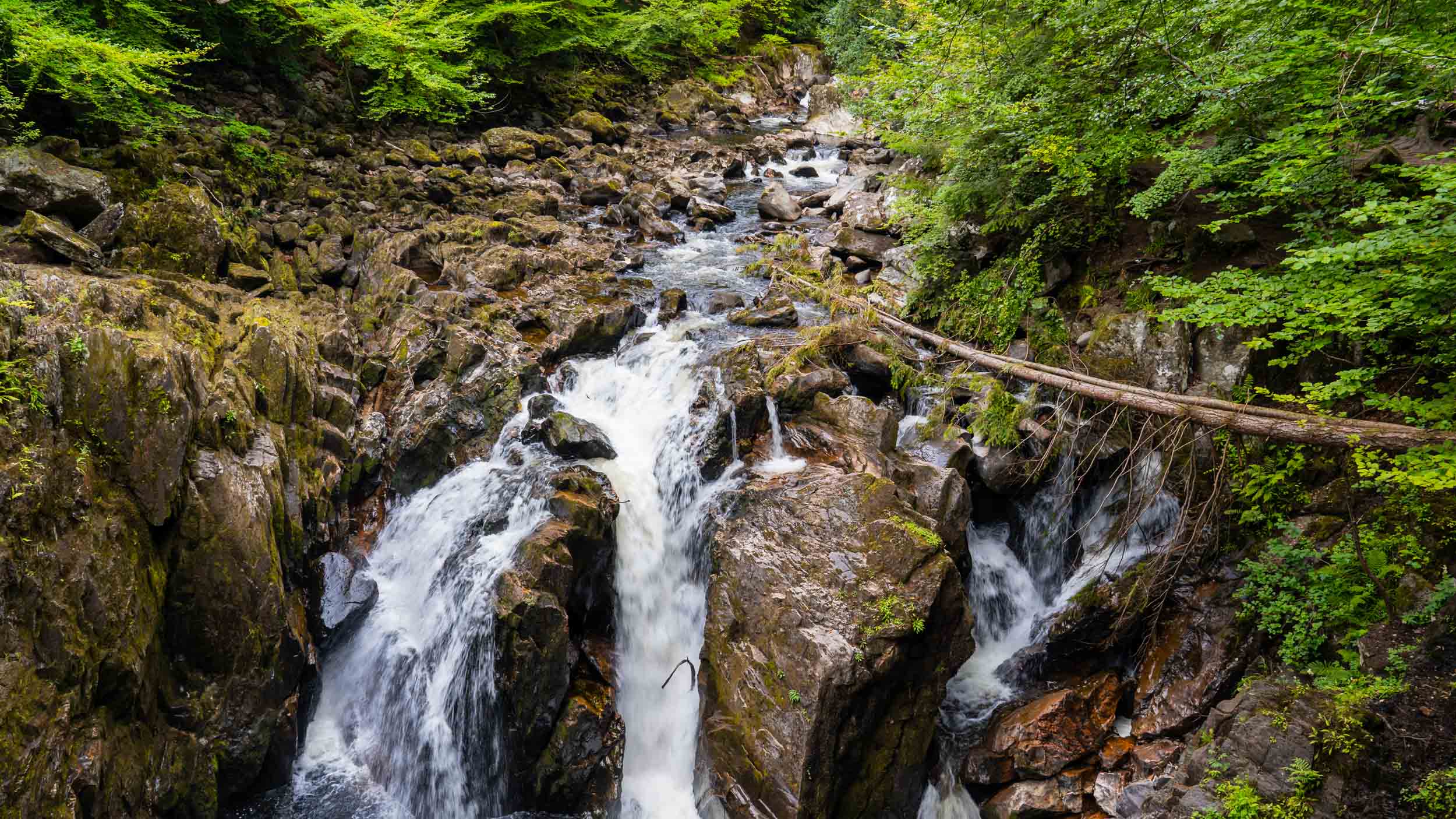 A serene cascade flowing over rocks surrounded by lush greenery, showcasing the natural beauty of the UK landscape.